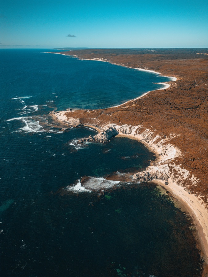Aerial view of an ochre headland and deep blue sea